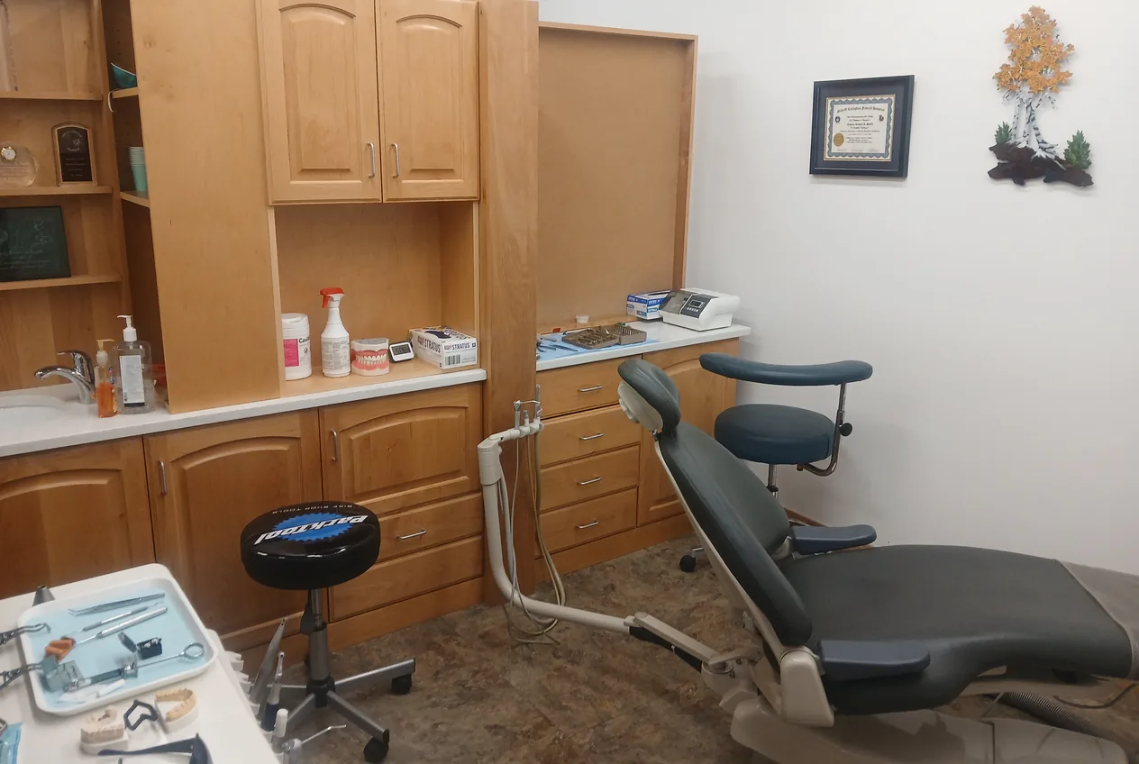 Treatment room with wood cabinets, a dental chair and an instrument tray set out for a visit.